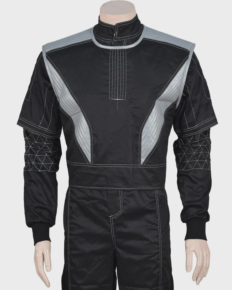 Puede incluir: Una chaqueta de estilo carreras en color negro con cuello alto, paneles acolchados plateados en los hombros y costuras blancas en contraste. Las mangas presentan un patr&oacute;n geom&eacute;trico triangular, con una cintura ancha y pu&ntilde;os acanalados negros.