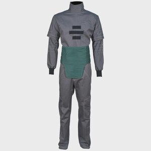 May include: A charcoal gray jumpsuit featuring a high collar, long sleeves with ribbed cuffs, and white contrast stitching. The garment includes a solid dark green waist panel and three horizontal black rectangular patches on the chest area.
