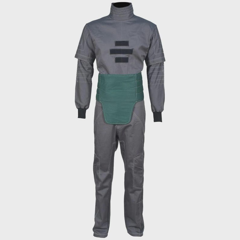 May include: A charcoal gray jumpsuit featuring a high collar, long sleeves with ribbed cuffs, and white contrast stitching. The garment includes a solid dark green waist panel and three horizontal black rectangular patches on the chest area.