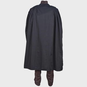 May include: A long, solid black cape with a high collar featuring a subtle brown pinstripe pattern. The cape is draped over a pair of matching brown trousers that also display a thin, vertical pinstripe design and visible white stitching.