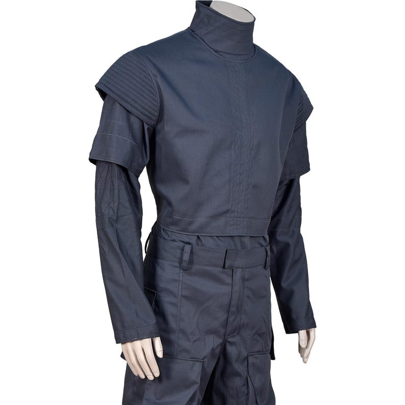 Peut inclure: Un ensemble uniforme bleu marine fonc&eacute; compos&eacute; d'un haut &agrave; col montant avec des panneaux d'&eacute;paules structur&eacute;s et c&ocirc;tel&eacute;s et des manches longues, associ&eacute; &agrave; un pantalon assorti dot&eacute; d'une ceinture &agrave; passants et de grandes poches cargo.