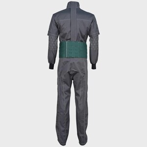 May include: A dark gray jumpsuit featuring long sleeves with white geometric stitching patterns on the forearms, a central vertical seam, and a wide, solid dark green belt secured around the waist. The garment has a structured collar and straight legs.