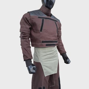 Puede incluir: Una chaqueta marr&oacute;n de manga larga con cuello alto, paneles negros en los hombros y detalles rectangulares negros. Presenta costuras blancas en contraste, combinada con una faja gris claro y pantalones marrones a juego sobre un maniqu&iacute;.