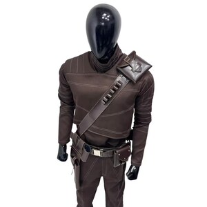 Peut inclure: Un ensemble haut &agrave; manches longues et pantalon marron fonc&eacute; avec des surpiq&ucirc;res claires. La tenue comprend une bandouli&egrave;re diagonale avec de petites boucles cylindriques, une pochette d'&eacute;paule et une ceinture utilitaire avec plusieurs poches.
