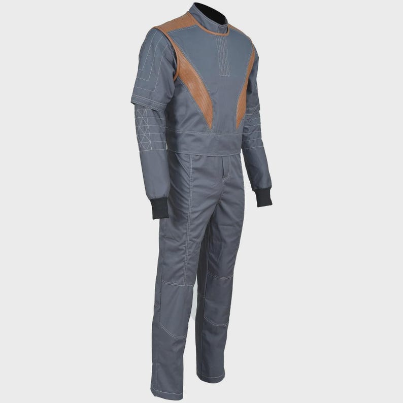 May include: A gray jumpsuit featuring tan leather-like panels on the chest and shoulders. The garment includes long sleeves with black ribbed cuffs, a high collar, and white contrast stitching details on the arms and legs for a structured look.