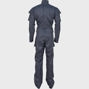 Peut inclure: Une combinaison gris fonc&eacute; dot&eacute;e d'un col montant, de manches longues avec des d&eacute;tails c&ocirc;tel&eacute;s aux &eacute;paules et d'une taille ajust&eacute;e avec un passant de ceinture. Le v&ecirc;tement comprend un pantalon droit avec poches lat&eacute;rales, vu de dos.