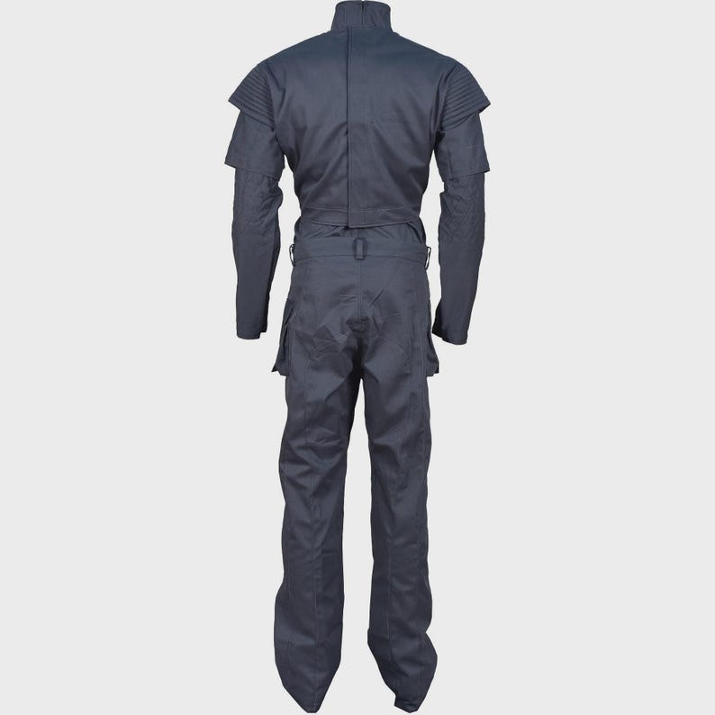 Peut inclure: Une combinaison gris fonc&eacute; dot&eacute;e d'un col montant, de manches longues avec des d&eacute;tails c&ocirc;tel&eacute;s aux &eacute;paules et d'une taille ajust&eacute;e avec un passant de ceinture. Le v&ecirc;tement comprend un pantalon droit avec poches lat&eacute;rales, vu de dos.