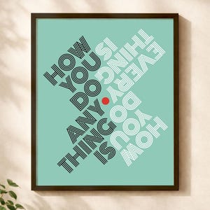 May include: Framed art print with the text "HOW YOU DO ANYTHING IS HOW YOU DO EVERYTHING" in black and white, set against a teal background. A small red dot is centered on the artwork. The frame is dark brown.