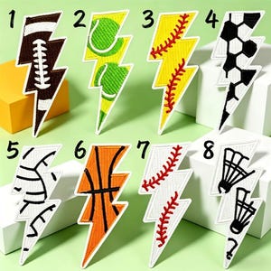 May include: Eight embroidered lightning bolt patches featuring sports themes: 1. brown football, 2. green tennis balls, 3. yellow softball, 4. black and white soccer ball, 5. white volleyball, 6. orange basketball, 7. white baseball, 8. white badminton shuttlecocks.