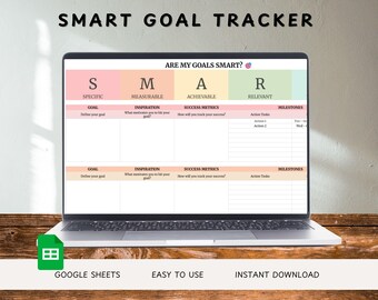 Könnte beinhalten: Ein Laptop zeigt eine SMART GOAL TRACKER Vorlage mit Abschnitten für spezifische, messbare, erreichbare und relevante Ziele. Der Bildschirm hat ein rosa, gelbes, grünes und orangefarbenes Farbschema. Der Laptop steht auf einer Holzoberfläche. Der Text unten lautet: "GOOGLE SHEETS, EASY TO USE, INSTANT DOWNLOAD."