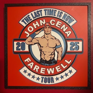 May include: A framed artwork featuring John Cena saluting, with text reading "THE LAST TIME IS NOW JOHN CENA FAREWELL TOUR 2025." The design is set against a red background with a black border, and includes blue and white accents.