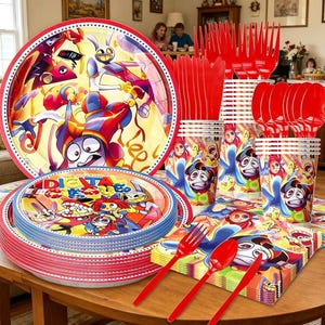 May include: A party supply set featuring The Amazing Digital Circus theme, including round paper plates with colorful character graphics, red plastic forks, red plastic spoons, red plastic knives, paper cups, and square paper napkins.