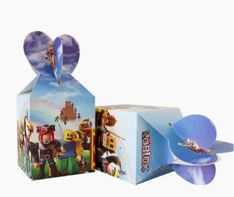 Puede incluir: Dos cajas de regalo rectangulares de cart&oacute;n con gr&aacute;ficos de personajes de Roblox y el logotipo de Roblox. Las cajas tienen un fondo de cielo azul claro con nubes y un arco&iacute;ris. La parte superior tiene solapas entrelazadas en forma de coraz&oacute;n.