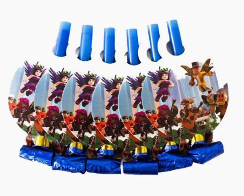 Puede incluir: Un conjunto de matracas de fiesta con recortes de cart&oacute;n circulares que muestran gr&aacute;ficos de personajes estilo bloque con trajes morados y dorados. Cada matraca tiene una boquilla de papel aluminio azul met&aacute;lico y un tubo de pl&aacute;stico azul.