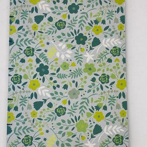 May include: A gray journal with a floral pattern featuring green and yellow flowers on a white background.