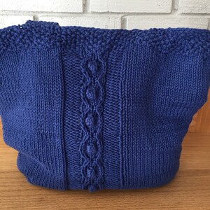 May include: A blue knitted tote bag with a cable knit design and a textured stitch pattern.