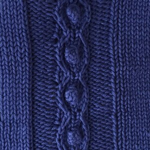 May include: A close-up of a blue knitted fabric with a cable knit pattern and decorative buttons.