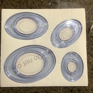 May include: Four clear plastic oval-shaped craft punches with different sizes. The punches are on a white background.