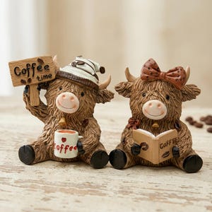 May include: Two brown highland cow figurines. The left cow wears a white hat, holds a sign reading Coffee time, and holds a white mug with the word Coffee. The right cow wears a brown polka-dot bow and holds an open book labeled Coffee.
