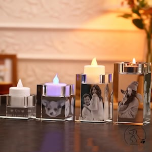 Könnte beinhalten: Vier klare Glas-Kerzenhalter mit personalisierten Fotos und LED-Kerzen. Die quadratischen Halter zeigen Bilder von Menschen und einem Hund. Die Kerzen erzeugen ein warmes, einladendes Licht.