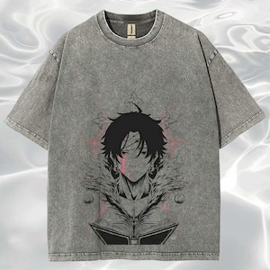May include: Gray, short-sleeved t-shirt with a graphic of a manga-style character. The character has black hair and a red streak on the face. The design includes a star and an open book. The shirt has a vintage, washed look.