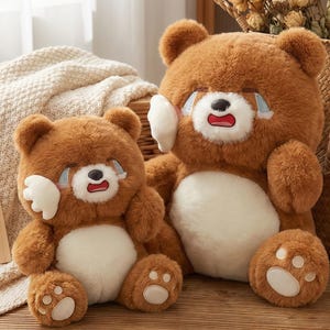May include: Two brown plush teddy bears with crying faces. The bears have white accents on their faces and paws. One bear is larger than the other. The bears are sitting on a wooden surface.
