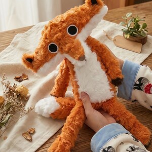 May include: A plush fox toy with orange fur, white chest and paws, and large black eyes. The fox has a long snout and ears with black tips. The toy is soft and cuddly, perfect for children.