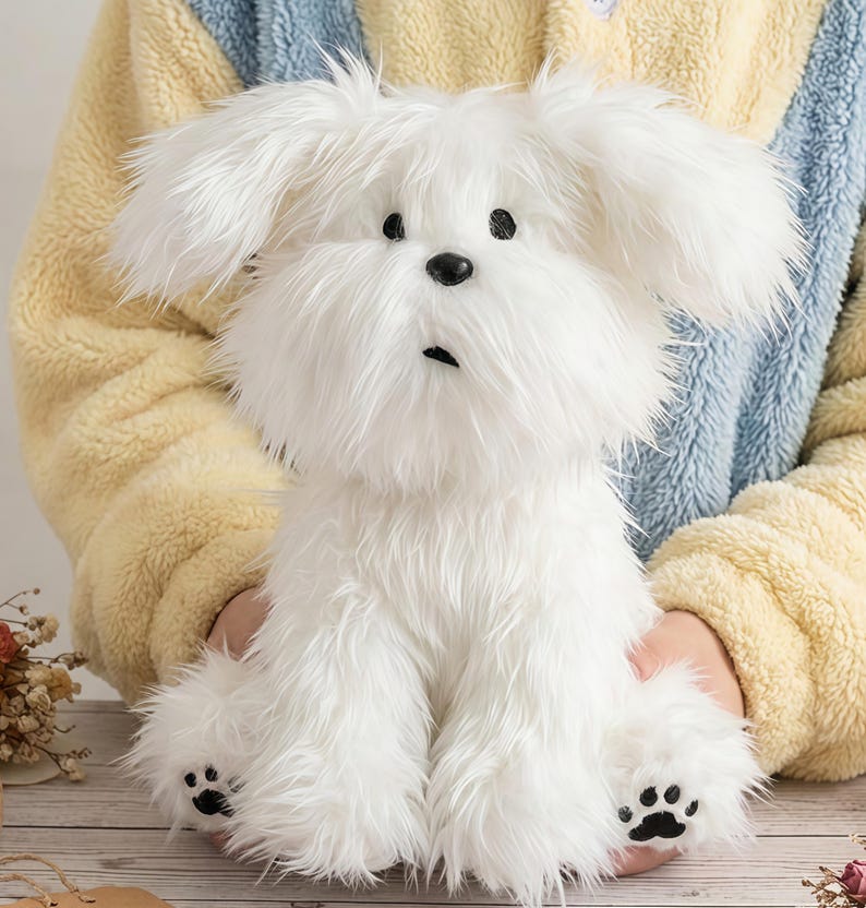 May include: A fluffy white plush dog with black eyes and a black nose. The stuffed animal has a long, shaggy coat and black paw prints on its feet. The dog is sitting upright.