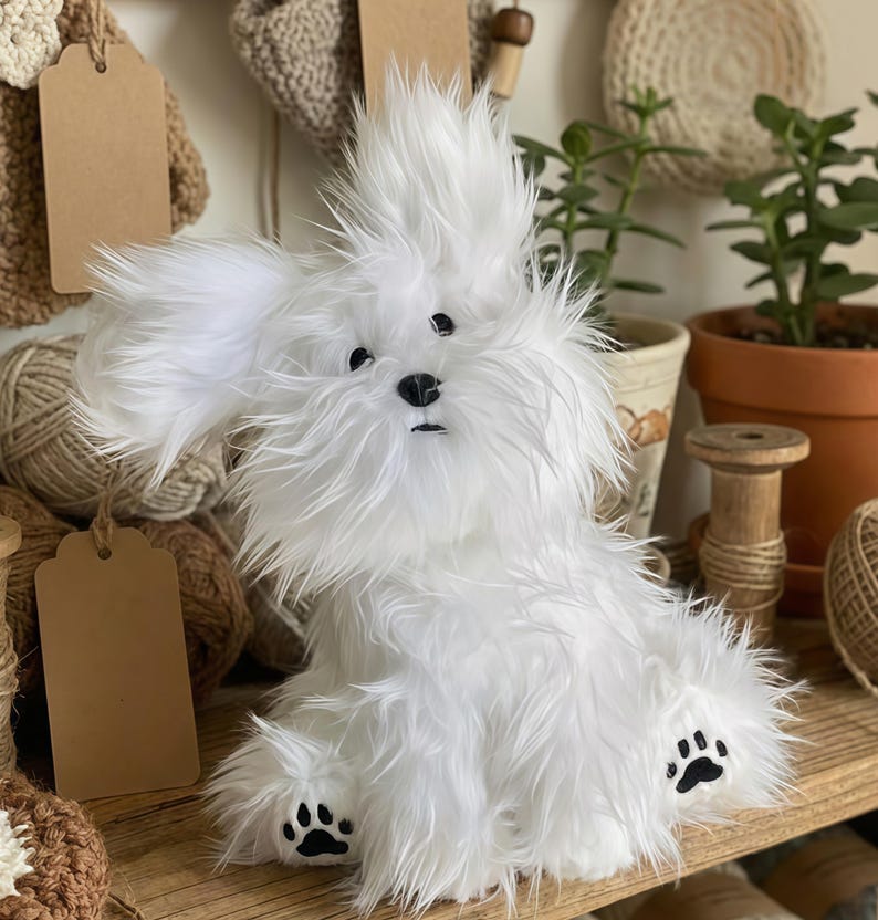 May include: A fluffy white plush dog with black paw prints and a black nose. The dog has long, shaggy fur and large, floppy ears. It is sitting on a wooden shelf with other craft supplies.