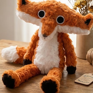 May include: A plush fox toy with orange and white fur, large black eyes, and a white-tipped tail. The fox is sitting on a wooden surface. The toy has black paws and a brown nose.