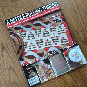 May include: A magazine titled A Needle Pulling Thread featuring articles on quilting, sewing, knitting, crochet, cross stitch, embroidery, and rug hooking. The cover displays a quilt with brown and white leaf patterns and red accents.