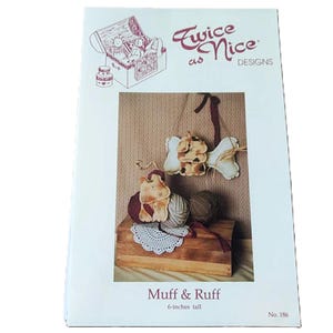 May include: A white craft pattern envelope titled Twice as Nice Designs featuring Muff & Ruff. The cover displays two small stuffed animal figures, one hanging and one sitting on yarn balls, with the text 6-inches tall and No. 186.