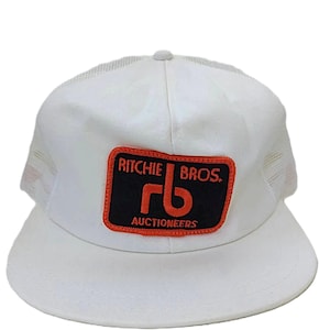 May include: A white ceramic mug with a black handle and the text "But First, Coffee" in a bold, black font. The mug is set against a neutral background, highlighting its simple design.