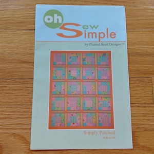 May include: A rectangular sewing pattern booklet titled Oh Sew Simple by Planted Seed Designs. The cover features a light blue and pale green background with a central image of a quilt made of pink, blue, and orange square patches.