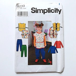 May include: A Simplicity sewing pattern envelope labeled 8233 for sizes AA 2, 3, 4. The cover features illustrations and a photograph of a child wearing a sleeveless tabard over a long-sleeved shirt and pants, showcasing various color options.
