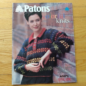 May include: A vintage Patons knitting pattern book cover showing a woman in a colourful knit sweater. The sweater has a red collar and buttoned placket. The cover text reads "Patons colourful knits."