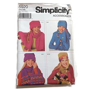 May include: A Simplicity Accessories sewing pattern envelope, number 5920, featuring illustrations of various knitted hats, scarves, and gloves in multiple colours including pink, blue, and purple, with a barcode and text printed on the white packaging.
