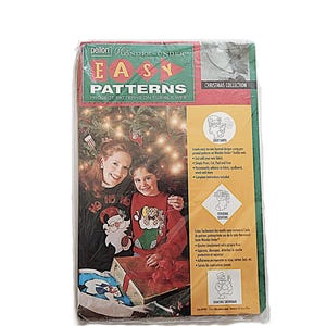 May include: A packaged Christmas craft pattern set. The package features the text "Pellon Wonder-Under Easy Patterns Christmas Collection". The image shows a woman and child wearing Christmas sweaters. The package includes patterns for Santa, stockings, and a snowman.