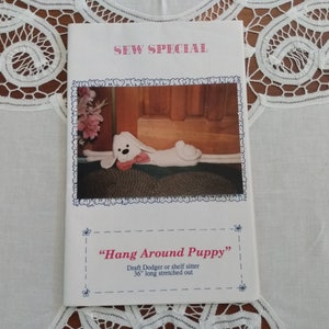 May include: A sewing pattern booklet titled "SEW SPECIAL" featuring a white stuffed puppy with a pink bow. The text "Hang Around Puppy" is displayed, with a description of the item as a draft dodger or shelf sitter, 36 inches long.