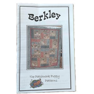 May include: A white paper pattern booklet titled Berkley The Patchwork Puppy Patterns. The cover features a central rectangular image of a multi-coloured patchwork quilt with puppy motifs, and a small illustration of a brown puppy on a green blanket.