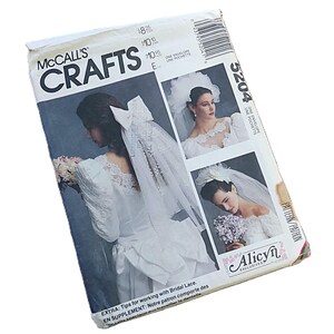 May include: A McCall's Crafts 5204 sewing pattern envelope featuring illustrations of bridal veils and headpieces. The white paper envelope displays text including McCall's Crafts, 5204, and Alicyn Exclusives, with images of individuals wearing white lace bridal attire and veils.