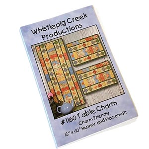 May include: A Whistlepig Creek Productions #1160 Table Charm pattern booklet featuring a 15 inch by 40 inch runner and placemats. The cover displays a quilted table runner and two placemats with a floral patchwork design and a small teapot.