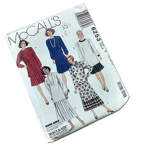 May include: A vintage McCall's sewing pattern featuring illustrations of dresses. The pattern envelope displays various dress designs in colors like red, blue, and white. The text "PETITE-ABLE" and "SELECT-A-SIZE" are visible.