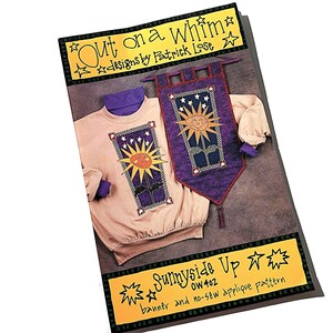 May include: A sewing pattern packet titled Out on a Whim designs by Patrick Lose featuring Sunnyside Up OW402 banner and no-sew applique pattern. The cover displays a beige sweatshirt and a purple fabric banner, both decorated with a sun and star motif.