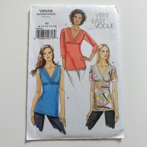 May include: A Very Easy Vogue sewing pattern envelope V8558 for sizes 8-16. The front displays illustrations of three tops with V-necklines and pleated details: a solid blue sleeveless top, a solid orange three-quarter sleeve top, and a patterned top.