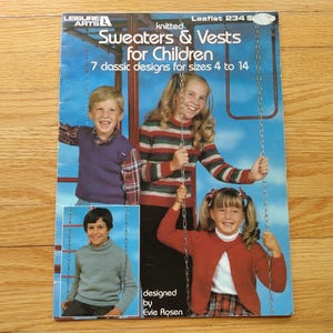 May include: A Leisure Arts knitting pattern leaflet titled Sweaters & Vests for Children, Leaflet 234. The cover features three children wearing knitted garments, including a purple vest, a striped sweater, and a red cardigan, with text.