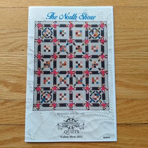 May include: A quilt pattern titled "The North Shore" with a finished size of 165 x 198 cm. The pattern features a repeating geometric design in shades of grey, black, red, and blue. The pattern is from Northwater Quilts.