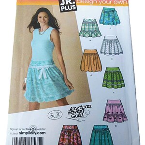 May include: A Simplicity sewing pattern envelope, number 4285, for JR. PLUS size BB 15/16-25/26. The front displays a model wearing a light blue skirt with a white ribbon tie, alongside illustrations of seven different skirt variations in various colours and patterns.