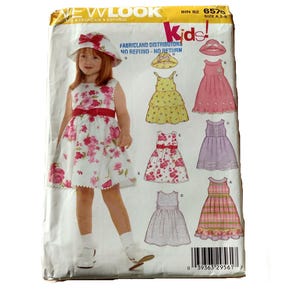 以下が含まれることがあります： 子供服用のNew Look 6576型紙封筒。表面には、赤いサッシュと揃いの帽子を合わせた白い花柄のドレスを着た子供が写っています。5種類のドレスのバリエーションと帽子のイラストが描かれており、下部にはバーコードがあります。
