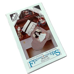 May include: A craft pattern packet for a 38 cm Yuletide Prairie Stocking by Finders Keepers. The cover features a red and white checkered stocking with a white lace cuff, displayed on a mantel with decorative figurines and full size patterns.